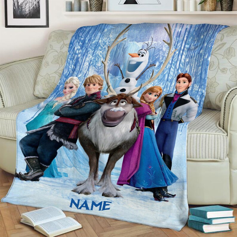 May include: A soft fleece throw blanket featuring a printed graphic of characters from the movie Frozen, including Elsa, Kristoff, Sven the reindeer, Olaf the snowman, Anna, and Hans, set against a snowy blue forest background with the word NAME.