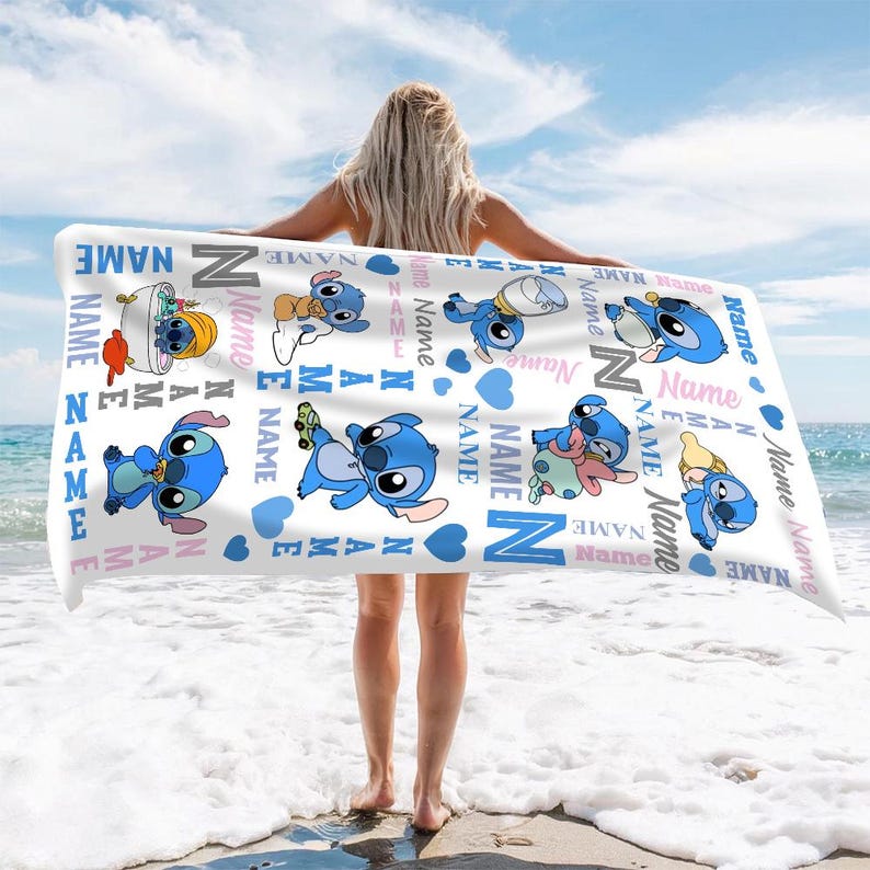 K&ouml;nnte beinhalten: Ein wei&szlig;es, rechteckiges Strandtuch mit einem sich wiederholenden Muster aus blauen Stitch-Figuren in verschiedenen Posen, durchsetzt mit blauen Herzen und dem Wort Name, das in verschiedenen Ausrichtungen in Blau, Grau und Pink aufgedruckt ist.