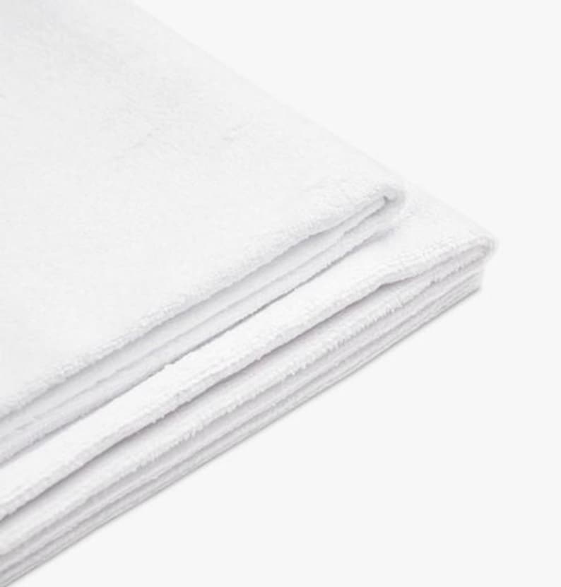 May include: A stack of folded, white, fluffy towels. The towels are made of a soft, absorbent material, and are neatly stacked on top of each other. The edges of the towels are visible, showing their thickness and texture.