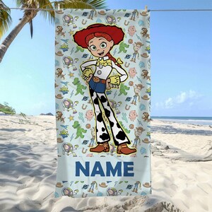 May include: A rectangular beach towel featuring a large central illustration of the character Jessie from Toy Story, surrounded by a repeating pattern of various characters and icons on a light blue background, with the word NAME printed at the bottom.