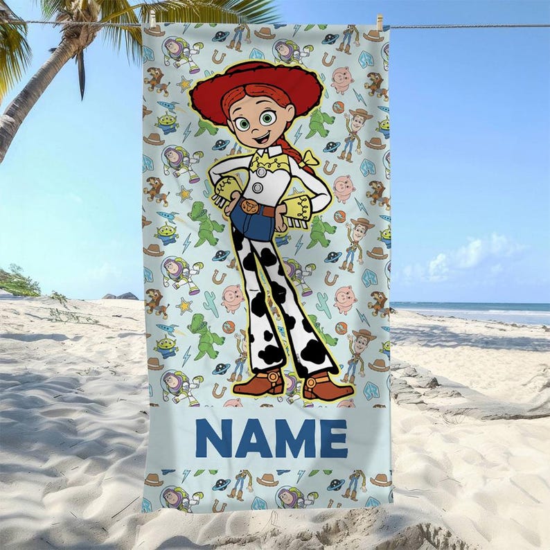 May include: A rectangular beach towel featuring a large central illustration of the character Jessie from Toy Story, surrounded by a repeating pattern of various characters and icons on a light blue background, with the word NAME printed at the bottom.