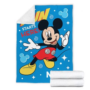 May include: A blue and white fleece blanket with a cartoon image of Mickey Mouse. The text "Fun Starts Here!" is printed on the blanket.