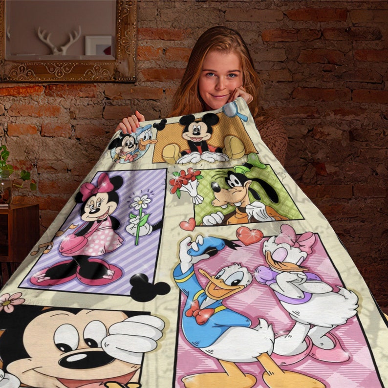 K&ouml;nnte beinhalten: Eine weiche Wohndecke mit einem mehrteiligen Grafikdruck klassischer Zeichentrickfiguren, darunter Mickey Maus, Minnie Maus, Donald Duck, Daisy Duck und Goofy. Das Design enth&auml;lt pastellfarbene Hintergr&uuml;nde, Herzmotive und Blumen.