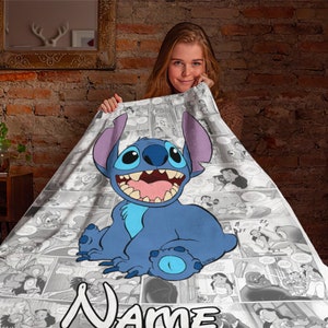 May include: A soft blanket featuring a large, colourful illustration of the blue character Stitch from Lilo and Stitch, centred over a black and white comic book panel background. The word Name is printed in large white letters at the bottom edge.