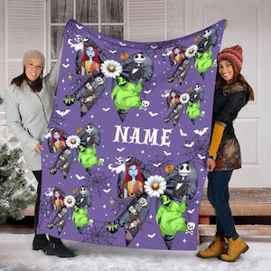 Puede incluir: Una manta morada con personajes de "Pesadilla antes de Navidad". El dise&ntilde;o incluye a Jack Skellington, Sally, Oogie Boogie y Zero, junto con telara&ntilde;as, murci&eacute;lagos y la palabra "NAME" en blanco. La manta est&aacute; sujeta por dos personas.