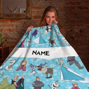 Pu&ograve; includere: Una coperta in pile azzurra con un motivo ripetuto di personaggi del film Frozen, tra cui Elsa, Anna, Olaf, Sven e Kristoff, su uno sfondo bianco con fiocchi di neve e una fascia orizzontale bianca centrale con la scritta NAME.