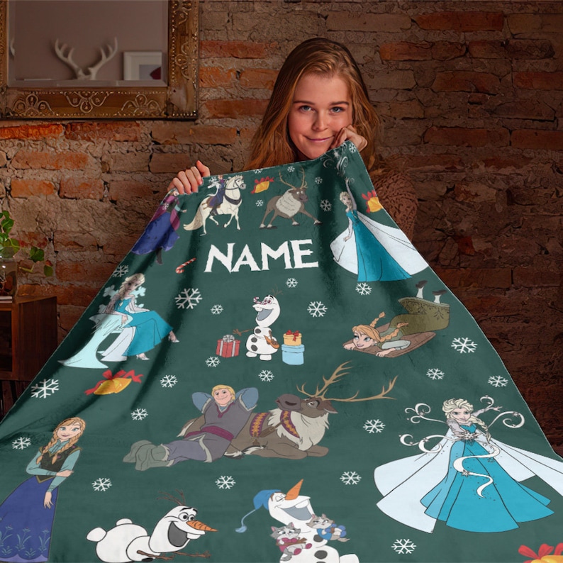 May include: A dark green fleece blanket featuring a repeating pattern of characters from the movie Frozen, including Elsa, Anna, Olaf, Kristoff, and Sven, interspersed with white snowflakes and the word NAME printed in white capital letters.