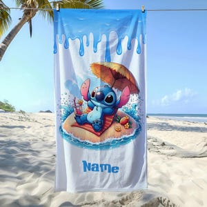 May include: White beach towel featuring a cartoon character relaxing on a tropical island. The blue and white towel has a blue border with dripping water design. The character is under a brown umbrella, with a drink in hand, and the word "Name" in blue.