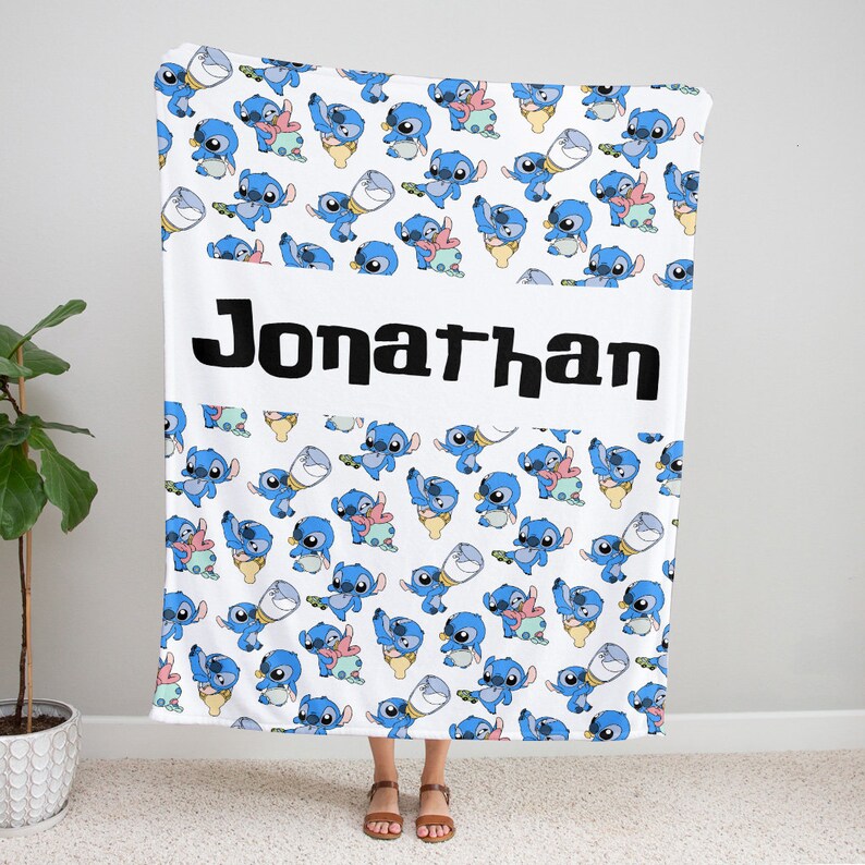 May include: A white fleece blanket featuring a repeating pattern of blue Stitch characters in various poses, including some holding cups. A wide horizontal white band across the center displays the name Jonathan in bold black lettering.