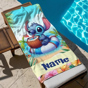May include: A beach towel featuring a cartoon character, Stitch, enjoying a coconut drink while floating on a blue and white striped inner tube. The towel has a tropical beach scene with the word "Name" in navy blue.
