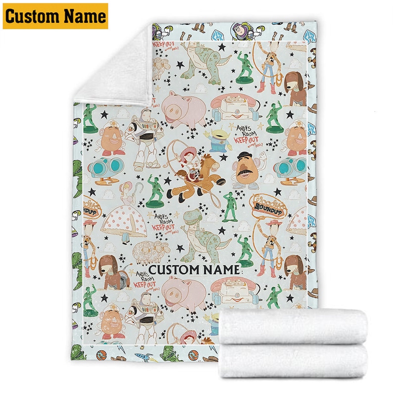 K&ouml;nnte beinhalten: Eine hellblaue Fleecedecke mit einem wiederkehrenden Muster aus Toy Story-Figuren wie Woody, Buzz Lightyear, Rex, Hamm und Mr. Potato Head. Das Design enth&auml;lt schwarze Sterne, den Text Andy's Room Keep Out sowie Custom Name.