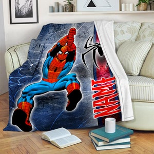 以下が含まれることがあります： 赤と青のスーツを着たスーパーヒーロー、スパイダーマンがクモの巣にぶら下がっているグラフィックが描かれたプラッシュブランケット。背景はダークブルーのテクスチャで、黒いクモのロゴと赤い太文字でNAMEという言葉がデザインされています。