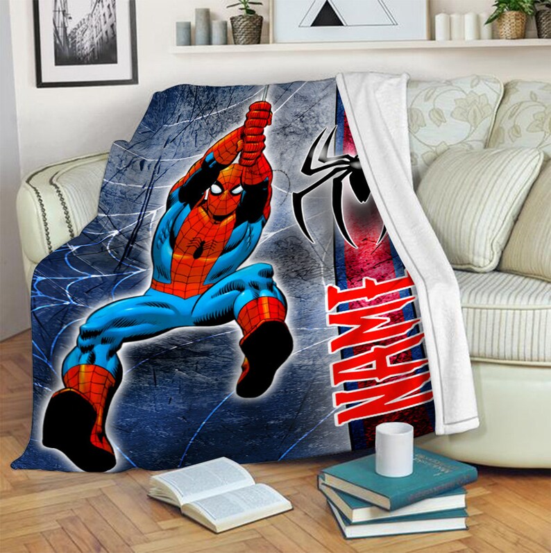 以下が含まれることがあります： 赤と青のスーツを着たスーパーヒーロー、スパイダーマンがクモの巣にぶら下がっているグラフィックが描かれたプラッシュブランケット。背景はダークブルーのテクスチャで、黒いクモのロゴと赤い太文字でNAMEという言葉がデザインされています。