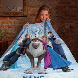May include: A soft fleece blanket featuring a printed graphic of characters from the movie Frozen, including Elsa, Anna, Kristoff, Olaf, and Sven the reindeer. The design is set against a snowy, icy blue background with the word NAME at the bottom.