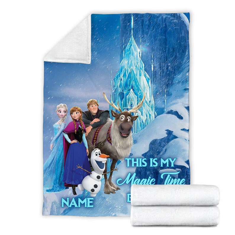 May include: A soft fleece blanket featuring a printed scene with characters Elsa, Anna, Kristoff, Sven, and Olaf in front of an ice castle. The text reads THIS IS MY Magic Time and includes a placeholder for a name in blue lettering.