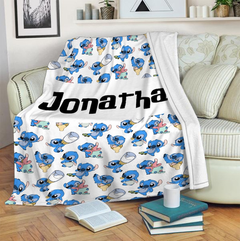 May include: A white fleece blanket featuring a repeating pattern of the blue character Stitch in various poses, including holding a bottle. The name Jonatha is printed in large, bold black letters across the center of the blanket.