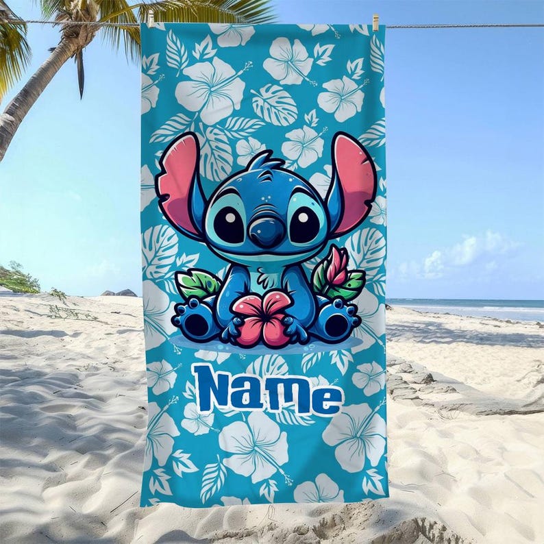 May include: A blue beach towel featuring a cartoon character holding a pink flower. The towel has a white floral pattern on a blue background. The word "Name" is printed in blue on the bottom.