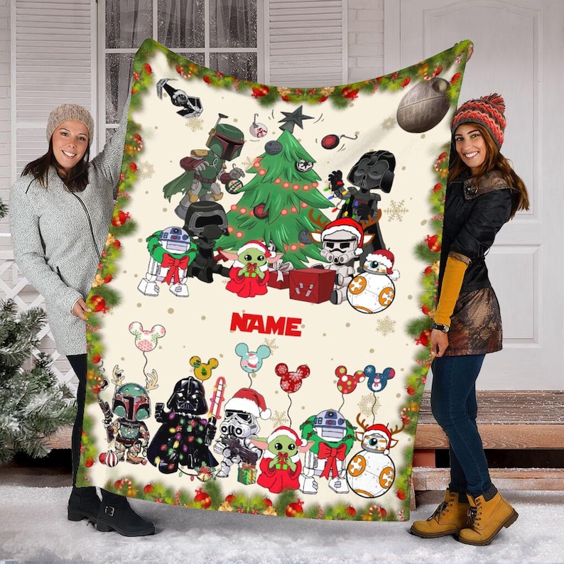 Puede incluir: Una manta de forro polar blanca con un tema navide&ntilde;o con personajes de Star Wars. La manta tiene un &aacute;rbol de Navidad verde, un gorro de Pap&aacute; Noel rojo y blanco, y una variedad de personajes de Star Wars, incluyendo Yoda, Darth Vader y Chewbacca. La manta tambi&eacute;n tiene un dise&ntilde;o de Mickey Mouse con el texto "NAME" en el centro.
