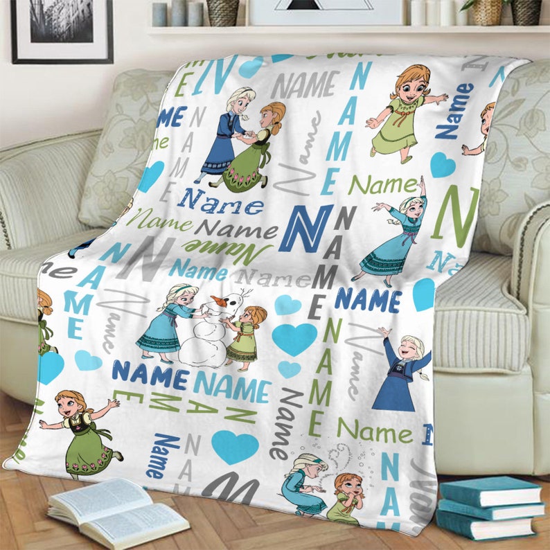May include: A white fleece blanket featuring a repeating pattern of cartoon characters Anna and Elsa, a snowman, and blue hearts. The design includes the word Name printed in various blue, green, and grey fonts, sizes, and orientations across the fabric.