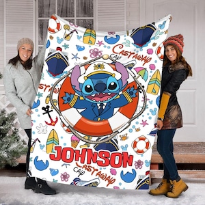 May include: A white fleece blanket with a colourful cartoon design featuring Stitch from Lilo & Stitch. The blanket has a blue and white striped background with a red life preserver and the text "Castaway Cap'n Johnson".