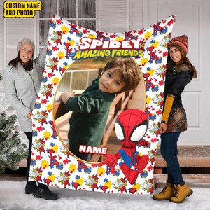 K&ouml;nnte beinhalten: Eine wei&szlig;e Fleecedecke mit dem Text Spidey and His Amazing Friends, einem zentralen ovalen Rahmen f&uuml;r ein individuelles Foto, einer Spider-Man-Cartoonfigur und einem wiederkehrenden Muster aus roten und gelben Sternen sowie einem Platzhalter f&uuml;r einen Namen.