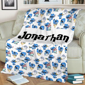 May include: A white fleece blanket featuring a repeating pattern of blue Stitch characters in various poses, including some holding baby bottles. The name Jonarhan is printed in large, bold, black sans-serif letters across the center.