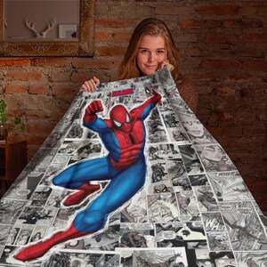May include: A soft throw blanket featuring a large, colorful illustration of Spider-Man in a dynamic leaping pose centered over a black and white comic book panel collage background. The word NAME is printed in red at the top of the blanket.