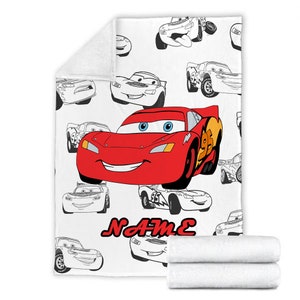 May include: A white fleece blanket featuring a repeating pattern of black and white line art of race cars. A large, colorful illustration of a red race car with blue eyes and the number 95 is centered. The word NAME is printed in red below the car.