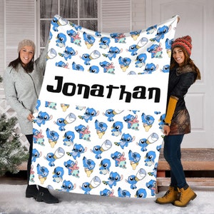 May include: A white fleece blanket featuring a repeating pattern of blue alien characters in various poses, interspersed with small baby bottles. A wide horizontal white band across the center displays the name Jonathan in bold black lettering.