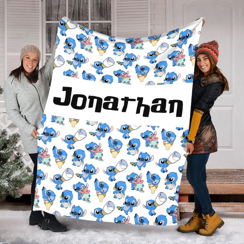 May include: A white fleece blanket featuring a repeating pattern of blue alien characters in various poses, interspersed with small baby bottles. A wide horizontal white band across the center displays the name Jonathan in bold black lettering.