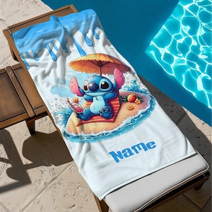 May include: A white beach towel featuring a cartoon character relaxing on a beach with an umbrella. The towel has a blue and white water design at the top and the word "Name" in blue at the bottom.