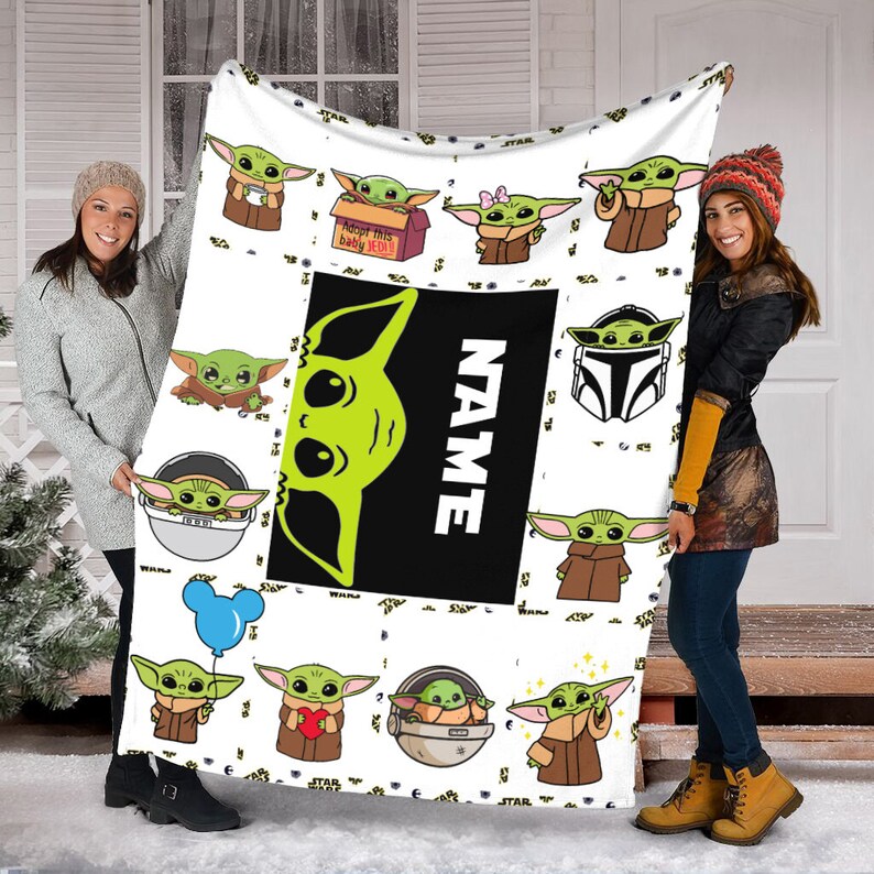 May include: A white fleece blanket featuring a repeating pattern of green alien characters in various poses, including one in a box labeled 'Adopt this baby JEDI!', one with a blue balloon, and one with a heart. A large black rectangle displays the word 'NAME'.