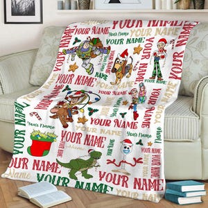May include: White fleece blanket with a Christmas theme featuring Toy Story characters. The blanket has a repeating pattern of the characters and the words "Your Name" throughout.
