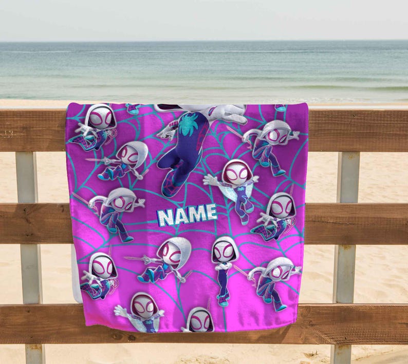 K&ouml;nnte beinhalten: Ein rechteckiges Strandtuch mit einem leuchtend pinkfarbenen Hintergrund und einem wiederkehrenden Muster aus Zeichentrickfiguren in wei&szlig;en, violetten und blauen Anz&uuml;gen, &uuml;berlagert von einem hellblauen Spinnennetz-Design und dem Wort NAME.