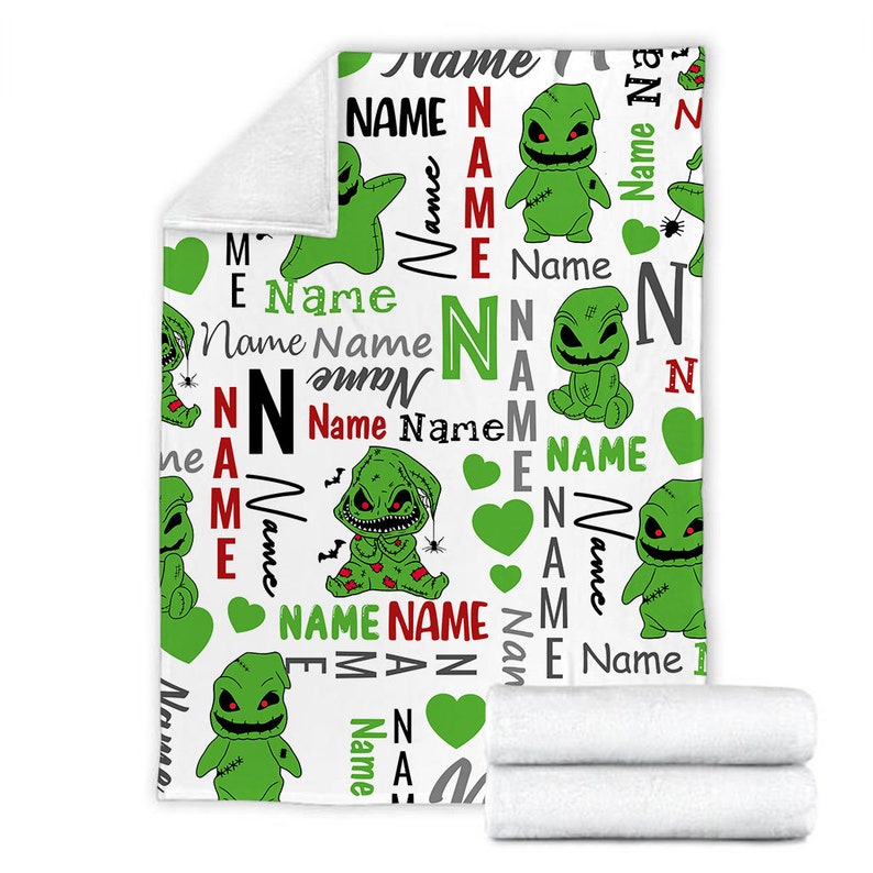 May include: White fleece blanket with a repeating pattern of green and black cartoon characters with the name "Name" repeated throughout the design.