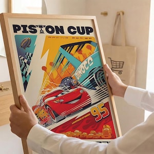 K&ouml;nnte beinhalten: Ein gerahmtes Poster mit einer dynamischen Rennszene. Das Poster zeigt ein rotes Rennauto mit der Nummer 95, den Text "Piston Cup" und andere Rennwagen. Der Hintergrund zeigt eine Zielflagge, ein Luftschiff und den Text "Dinoco."