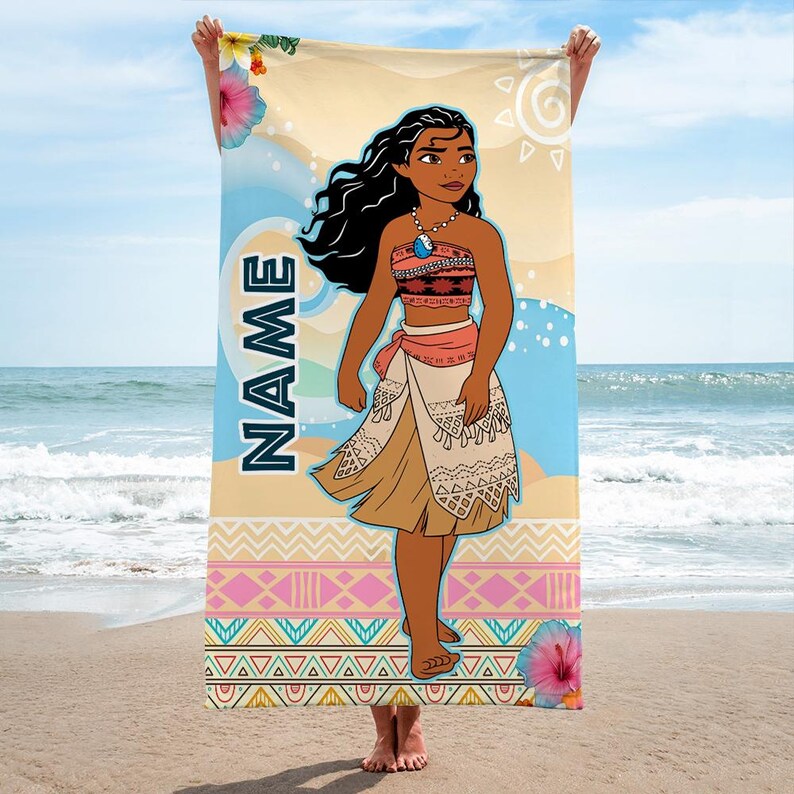 May include: A rectangular beach towel featuring a cartoon illustration of a young person with long dark hair, wearing a patterned top and skirt, and a blue necklace. The word NAME is printed vertically in blue, with hibiscus flowers and geometric patterns.