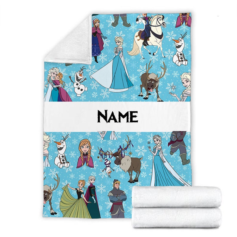 Pu&ograve; includere: Una coperta in pile azzurro con un motivo ripetuto di personaggi di Frozen, tra cui Elsa, Anna, Olaf, Sven e Kristoff, intervallati da fiocchi di neve bianchi. Un'ampia fascia orizzontale bianca al centro mostra la scritta NAME.