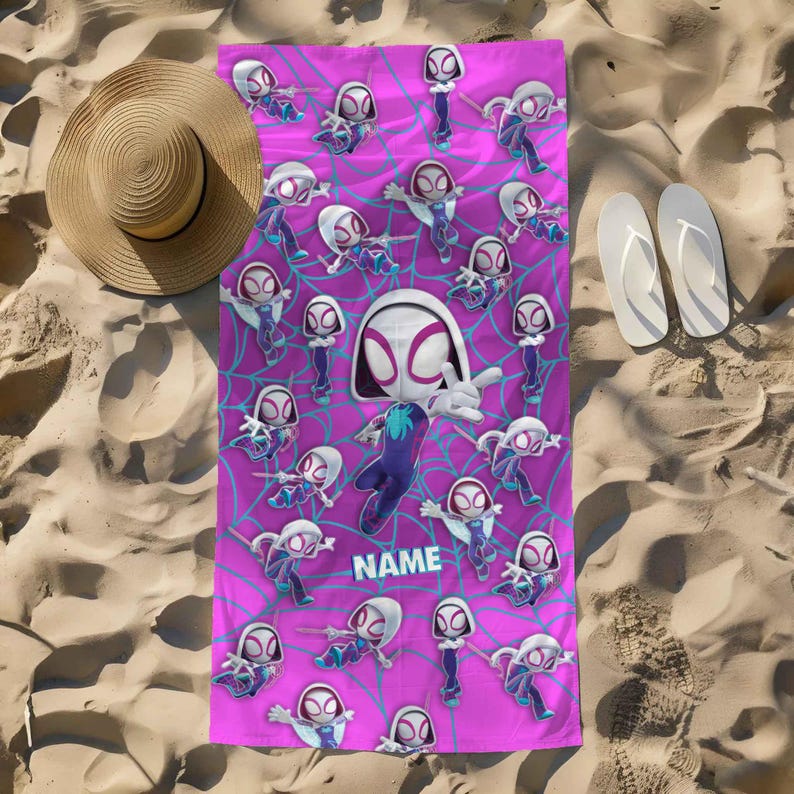 K&ouml;nnte beinhalten: Ein rechteckiges Strandtuch mit einem leuchtend pinkfarbenen Hintergrund, das ein wiederkehrendes Muster von Ghost-Spider-Figuren in verschiedenen Posen zeigt, &uuml;berlagert mit einem blauen Spinnennetz-Design und dem Wort NAME in blauen Buchstaben.