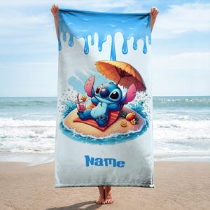 May include: A beach towel featuring a cartoon character relaxing on a small island with an umbrella and a drink. The towel has a blue and white design with the word "Name" in blue.