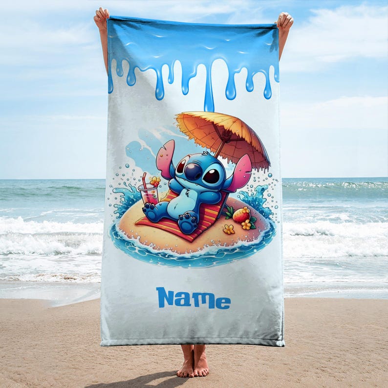 May include: A beach towel featuring a cartoon character relaxing on a small island with an umbrella and a drink. The towel has a blue and white design with the word "Name" in blue.