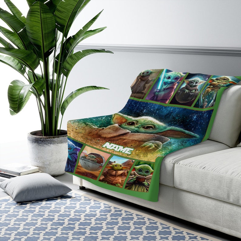 May include: A soft throw blanket featuring multiple graphic panels of a green, large-eared creature in various poses. The center displays a large image of the creature with the text NAME printed in white block letters against a dark blue background.
