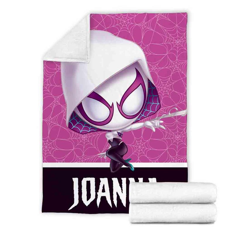 K&ouml;nnte beinhalten: Eine rosa-wei&szlig;e Fleece-Decke mit einem Cartoon-Bild einer wei&szlig;en Spinnenfrau in einem schwarzen Anzug mit einem Spinnennetz-Design. Die Decke tr&auml;gt den Namen "JOANNA" aufgedruckt.