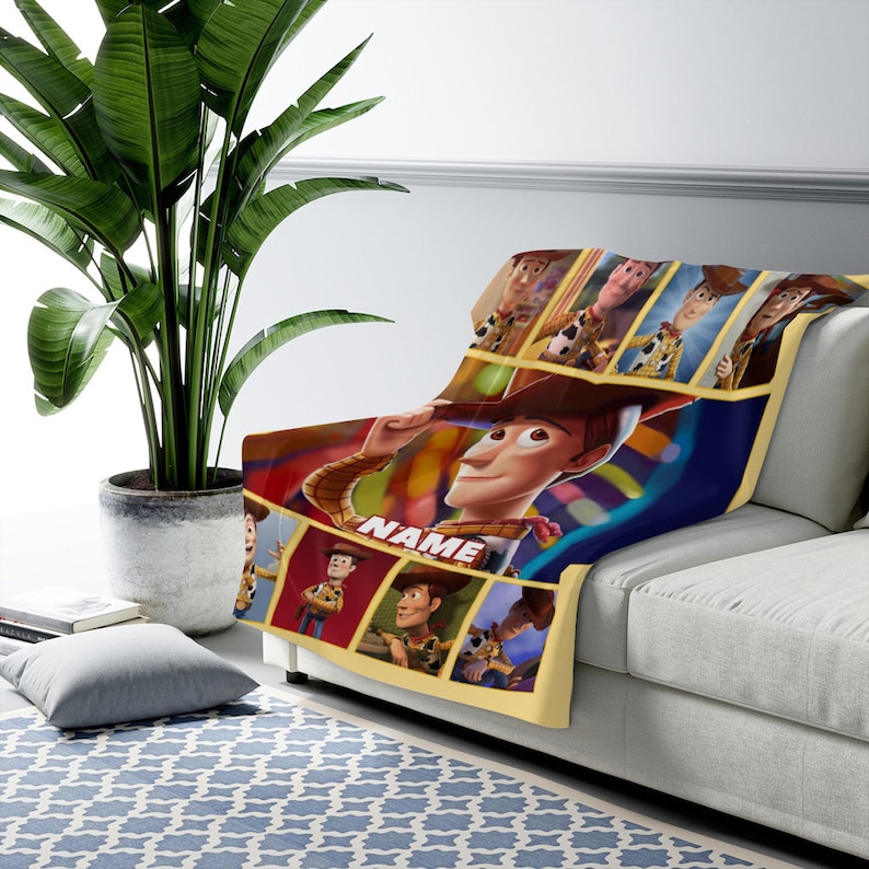 May include: A soft throw blanket featuring multiple panels of the character Woody from Toy Story in various poses. The central image shows Woody tipping his hat with the word NAME printed in white block letters below him on a dark blue background.