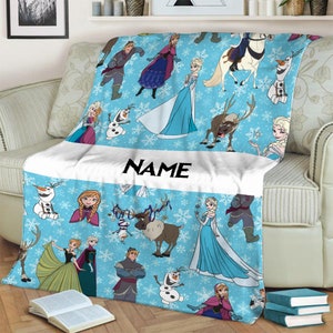 Pu&ograve; includere: Una coperta in pile azzurro con un motivo ripetuto di personaggi del film Frozen, tra cui Elsa, Anna, Olaf, Kristoff e Sven, su uno sfondo di fiocchi di neve bianchi con una fascia orizzontale bianca centrale che riporta la parola NAME.