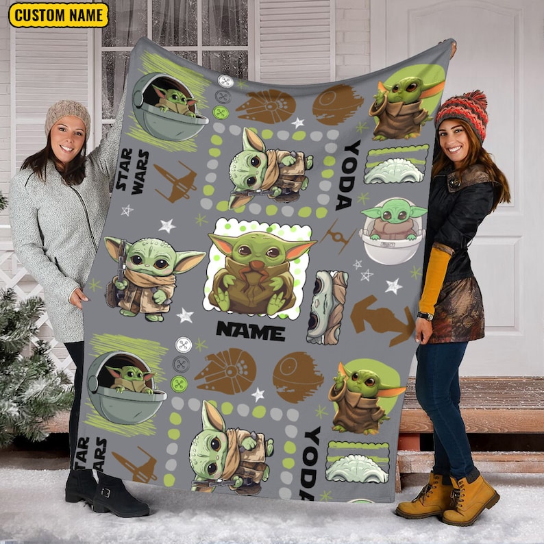 May include: A gray fleece blanket featuring a repeating pattern of the green character Grogu from Star Wars in various poses, including inside a floating pod. The design includes brown starship silhouettes, white stars, and the text CUSTOM NAME.