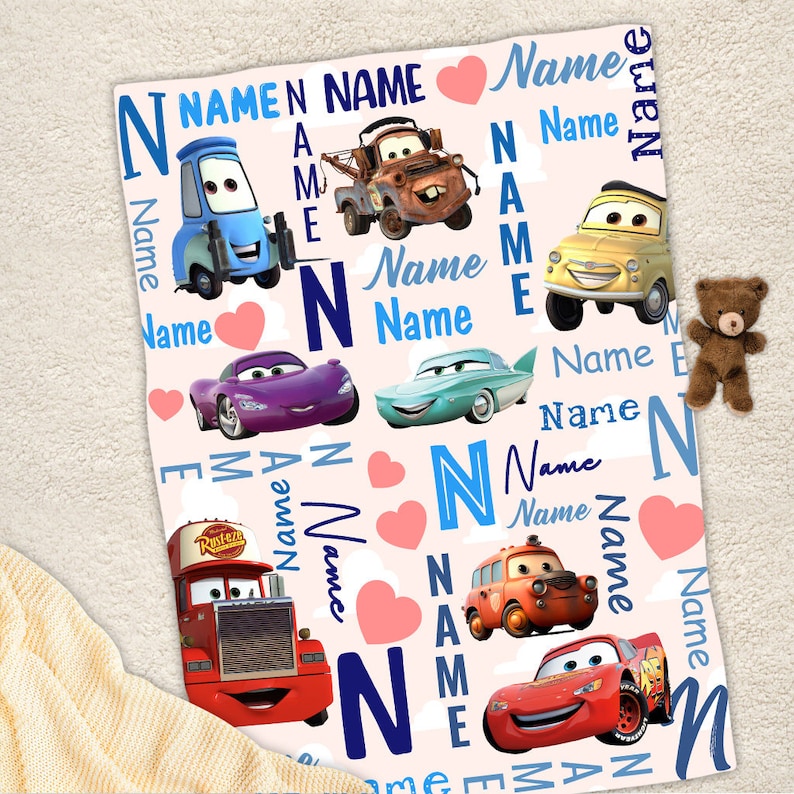 May include: A soft blanket featuring a repeating pattern of Disney Cars characters including Lightning McQueen, Mater, and Luigi. The design includes the word Name in various blue fonts, pink hearts, and the letter N on a light background.