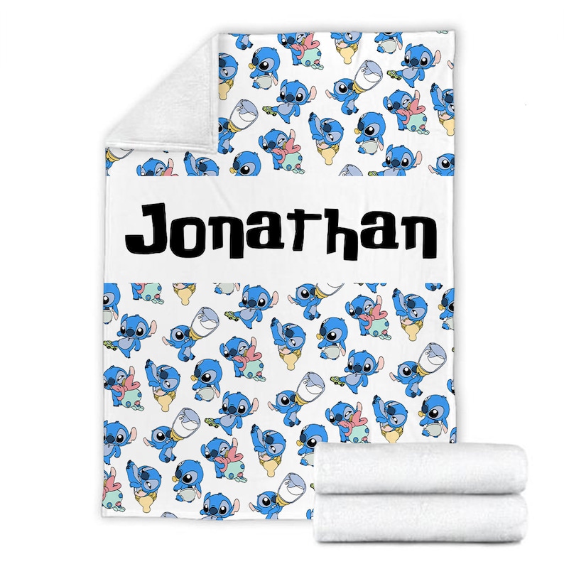 May include: A white fleece blanket featuring a repeating pattern of the blue character Stitch in various poses, including holding a baby bottle. A horizontal white band across the center displays the name Jonathan in bold black lettering.