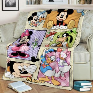 K&ouml;nnte beinhalten: Eine Pl&uuml;schdecke mit einem mehrteiligen Grafikdruck von Disney-Figuren, darunter Mickey Maus, Minnie Maus, Donald Duck, Daisy Duck und Goofy. Das Design enth&auml;lt einen Platz f&uuml;r einen Wunschnamen &uuml;ber dem gelben Schriftzug Name.