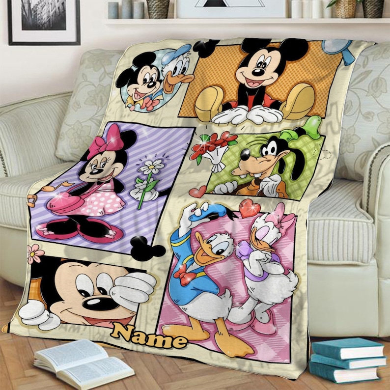 K&ouml;nnte beinhalten: Eine Pl&uuml;schdecke mit einem mehrteiligen Grafikdruck von Disney-Figuren, darunter Mickey Maus, Minnie Maus, Donald Duck, Daisy Duck und Goofy. Das Design enth&auml;lt einen Platz f&uuml;r einen Wunschnamen &uuml;ber dem gelben Schriftzug Name.